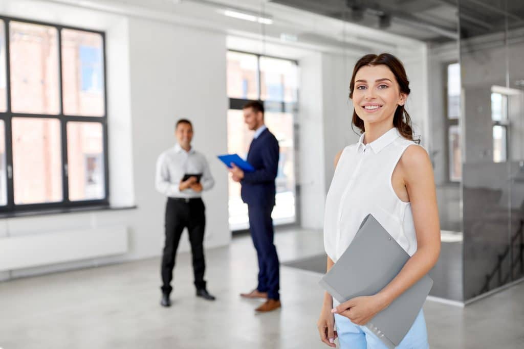 real estate business, sale and people concept - happy smiling realtor or businesswoman with folder and customers at new office room